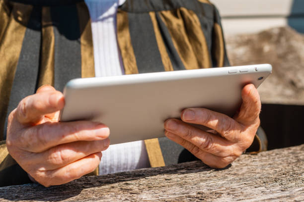 hände einer älteren frau, die einen tablet-pc hält, draußen an warmen sommertagen. aufschließen. selektiver fokus. - 11833 stock-fotos und bilder