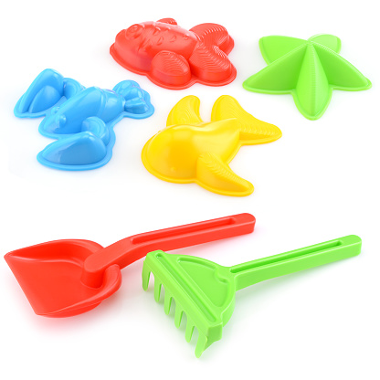 A set of children's toys for playing in the sandbox. Colored rake and shovel made of plastic, isolated on a white background, close-up. Early child development, children's leisure concept.