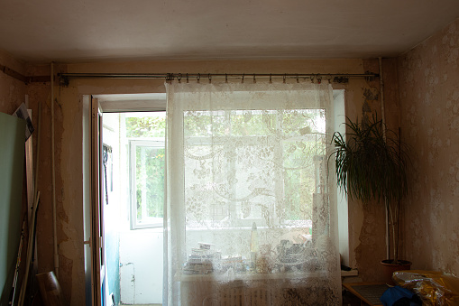 an old room with a window in a Soviet apartment in Ukraine without renovation with empty walls and torn wallpaper, a room before renovation, an empty room without renovation