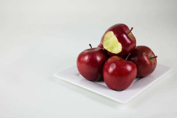 pile of red apples with one red apple bitten on white background. landscape photography