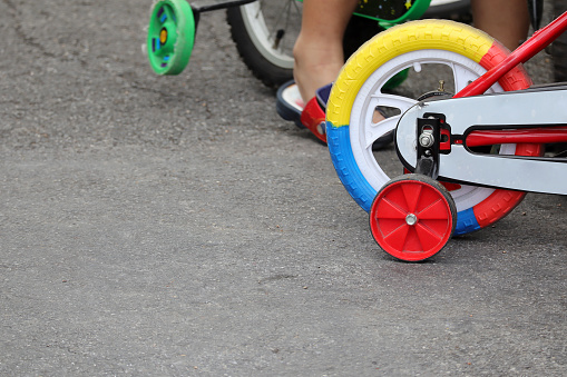 Close up of Red tricycle white wheels. Kid riding bicycle tricycle on the street in the park.