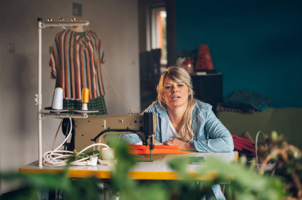 istock Tailor woman sitting and sewing on a sewing machine a in studio 1405558368