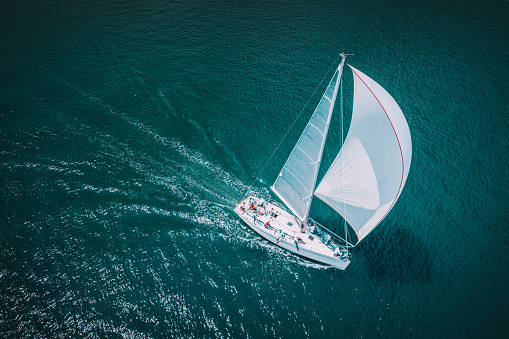 Regatta sailing ship yachts with white sails at opened sea. Aerial view of sailboat in windy condition