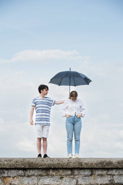 handsome young man holding umbrella above smiling young woman isolated on white