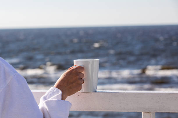 White coffw mug in a woman's hand on the terrace with sea view