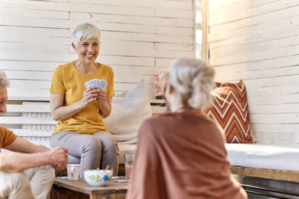 istock Happy senior friends talking while playing cards at home. 1405561048