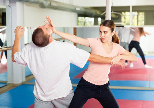 istock Young woman practicing palm strike with man in self defense training 1405561706