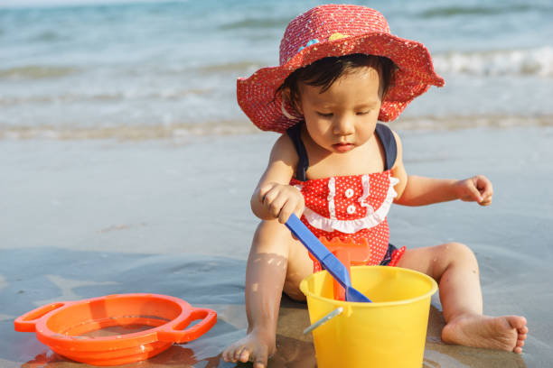 istock Small girl sitting on sand at beach 1405565477