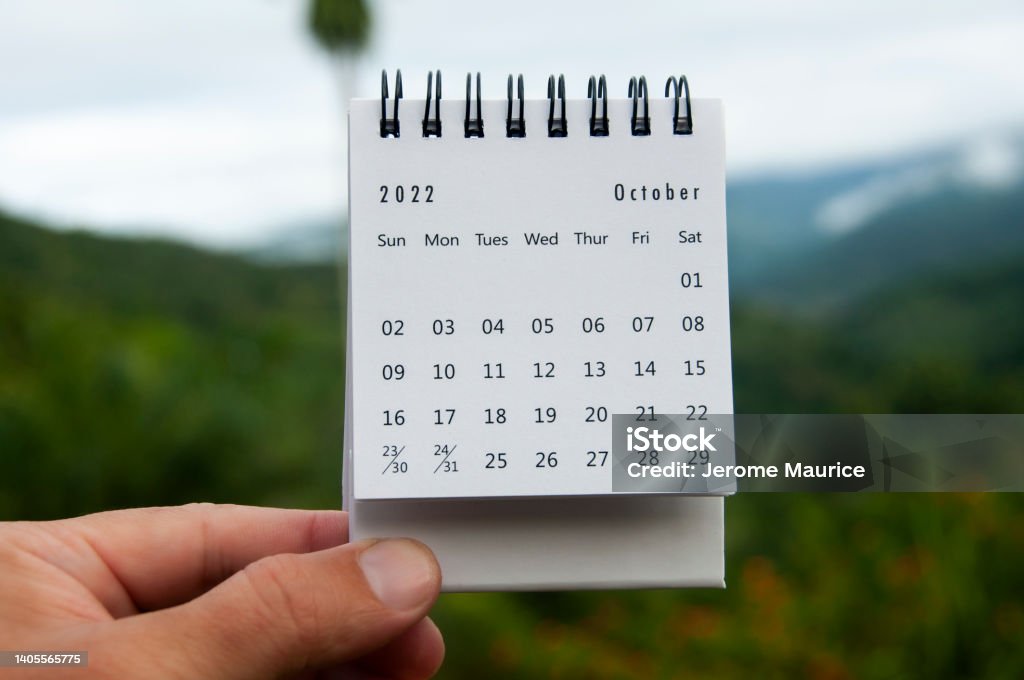 Hand holding October 2022 calendar with copy space and nature background. Hand holding October 2022 calendar with copy space. October Stock Photo