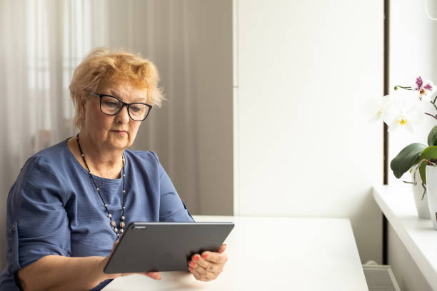 telemedicine concept, old woman with tablet pc during an online consultation with her doctor in her living room stock photo