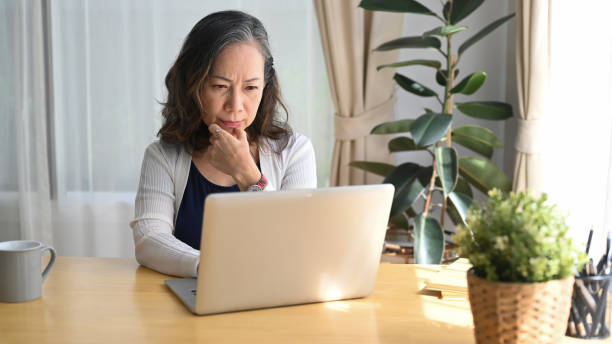 istock Serious mature woman checking business email during remote working from home. 1405567366