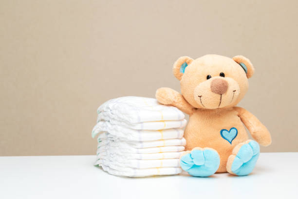 Stack of diapers with toy teddy bear on table. set for boy girl for baby shower with copy space Stack of diapers with toy teddy bear on table. set for boy girl for baby shower with copy space. baby shower stock pictures, royalty-free photos & images