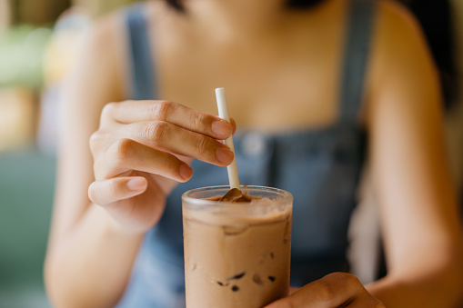 Image of an Asian Chinese woman drinking cold drink with a paper straw