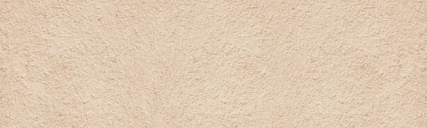 istock Old rough weathered plaster wide texture. Light golden beige painted textured cement aged cracked wall. Pastel color abstract panoramic grunge background 1405572991