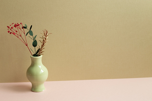Vase of dry flowers on pink table. beige wall background
