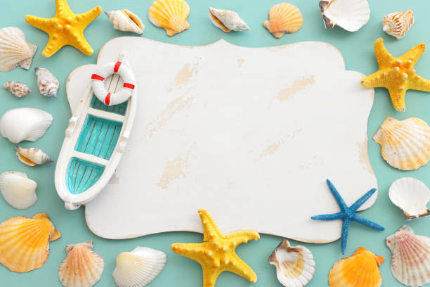 istock nautical concept with sail boat, seashells, star fish and blank board for copy space over mint blue wooden background 1405575505