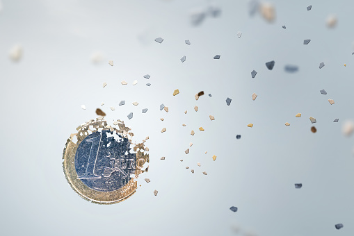 Economic concept. One Euro Coin breaking into small pieces. Isolated on neutral background.