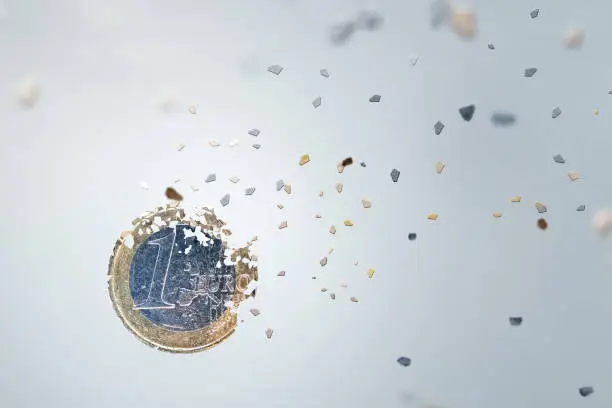Economic concept. One Euro Coin breaking into small pieces. Isolated on neutral background.