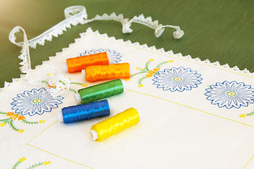Napkin with embroidery in the form of cornflowers and spools of thread located on it, with which embroidery and lace are made. Embroidery as a kind of creativity and needlework.