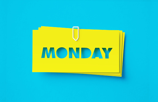 Monday written cut out yellow adhesive notes sitting on turquoise background. Horizontal composition with copy space.