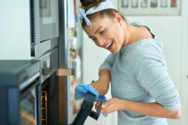 Young woman cleaning oven in the kitchen stock photo