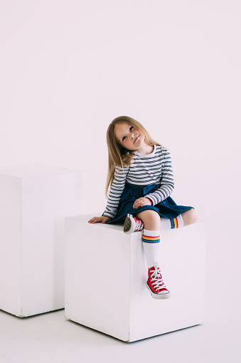 Two kids, brother and sister sitting on the box isolated solated over gray studio background. Children happy, cheerful. Copyspace for ad. Childhood, education, emotions, facial expression concept.