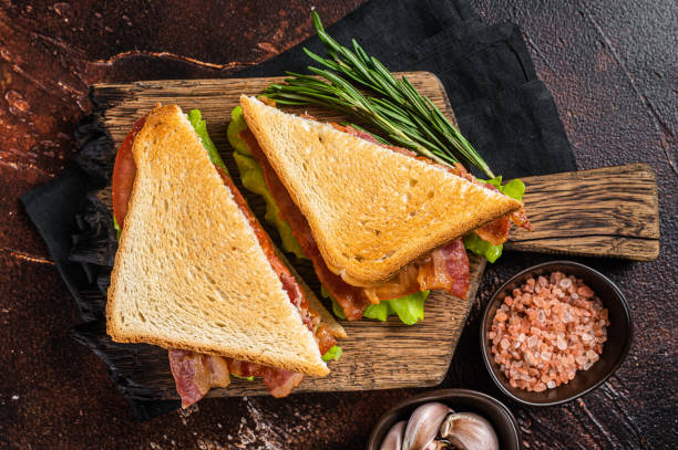 klasyczna kanapka blt z boczkiem, pomidorem i sałatą na drewnianej desce z ziołami. ciemne tło. widok z góry - sandwich delicatessen bacon lettuce and tomato mayonnaise zdjęcia i obrazy z banku zdjęć