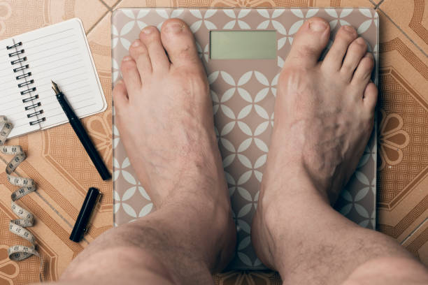 l'uomo si pesa su una bilancia digitale - weight scale dieting weight loss foto e immagini stock