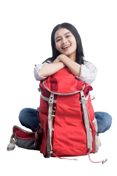 Asian woman sitting with her a backpack isolated over white background