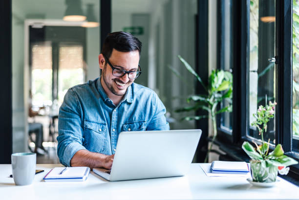 istock Smiling professional working on laptop while sitting at table in home office 1405588022