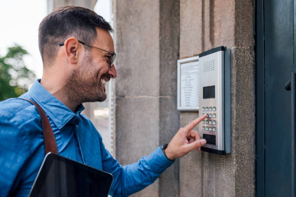 istock Smiling businessman using intercom while standing at entrance in the city 1405588745