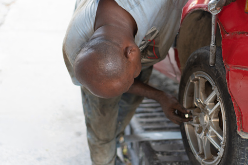 A senior mechanic at work repairing a car tire.