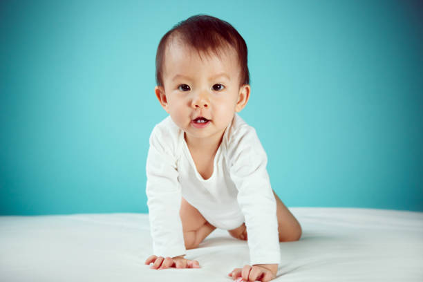 istock A crawling newborn in diaper with blue background (soft focus on the eyes) 1405590301