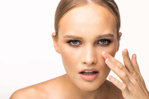 istock beautiful model applying cosmetic cream treatment on her face on white background 1405590721