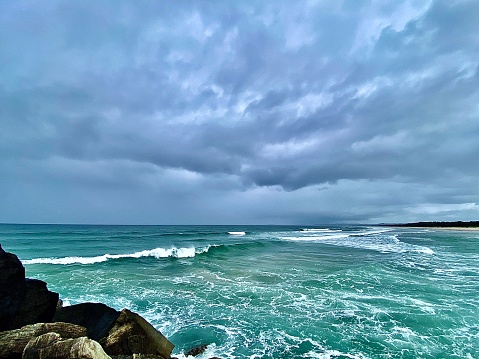 Horizontal seascape of wild green breaking waves on stormy grey day under a dramatic sky at Brunswick Heads NSW Australia