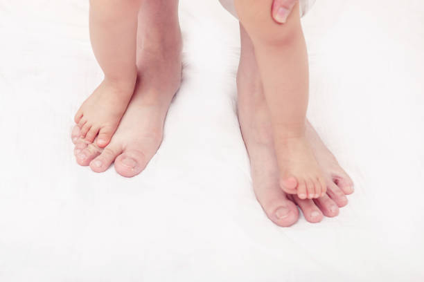 First steps. Baby learning to walk, with help of mothers and fathers. (Soft focus and blurry)