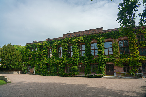 Lund, Sweden - June 9, 2022:  Old university building with lots of greenery. Palaestra et Odeum. Built in 1883. Behind the façade are also parts of the old orangery from the 1750s when this was a botanical garden. Palaestra et Odeum originally housed a fencing hall (i.e. a gymnasium) and a music room.