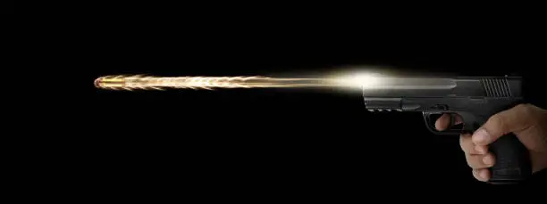Photo of The hand presses the trigger of the gun and the flame from the shot escapes from its muzzle