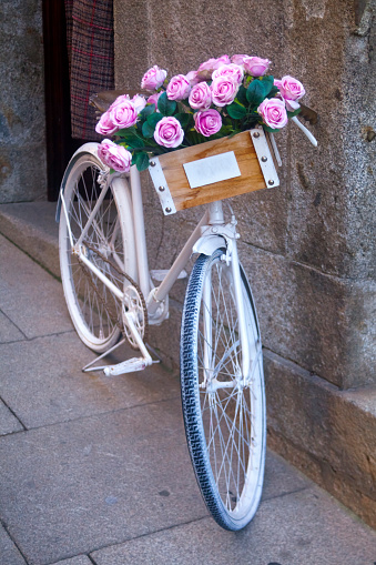 Old bicycle leaning in the street, decoration purposes, crate with beautiful rose flower bunch. Valença de Minho, Portugal.