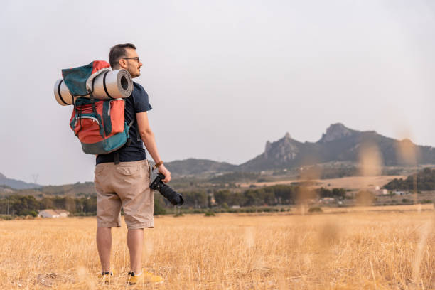istock Explorer with camera, backpack with mat, with relaxed and happy expression, in a meadow. Horizontal photography with copy space. 1405594395