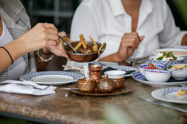 istock Holding copper bowl and taking meat dish with spoon, dinner party at restaurant table 1405595635