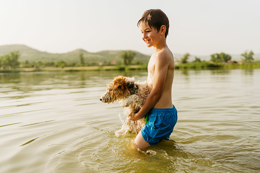Photo of a young boy and his dog spending a summer day on the lake.
