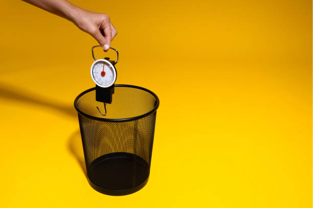 istock A hand throws a hand scale into the trash. Steelyard rushes into the office wastebasket. The concept of losing weight and getting rid of excess weight 1405597021