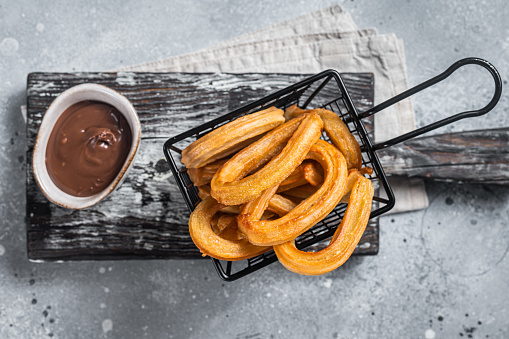 Traditional Spanish dessert churros with sugar and chocolate. Gray background. Top view.
