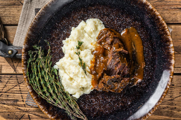 rinderbacken in rotweinsauce mit kartoffelpüree gedünstet. holzhintergrund. draufsicht - stewing steak stock-fotos und bilder