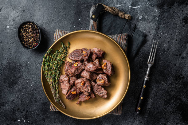 istock Chopped Grilled Diced Beef garlic steak on a plate with thyme. Black background. Top view 1405601145