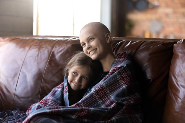 счастливая мама с раком и маленькая дочь, завернутая в плед - family television fighting watching стоковые фото и изображения