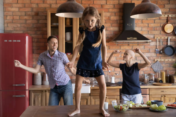 istock Excited kid dancing on kitchen table while parents moving bodies 1405601297