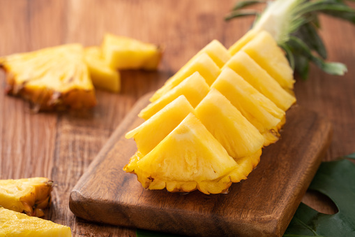 Close up of fresh cut pineapple on a tray over dark wooden table background.