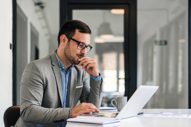 istock Confident businessman scrolling on laptop while working at desk in office 1405602527
